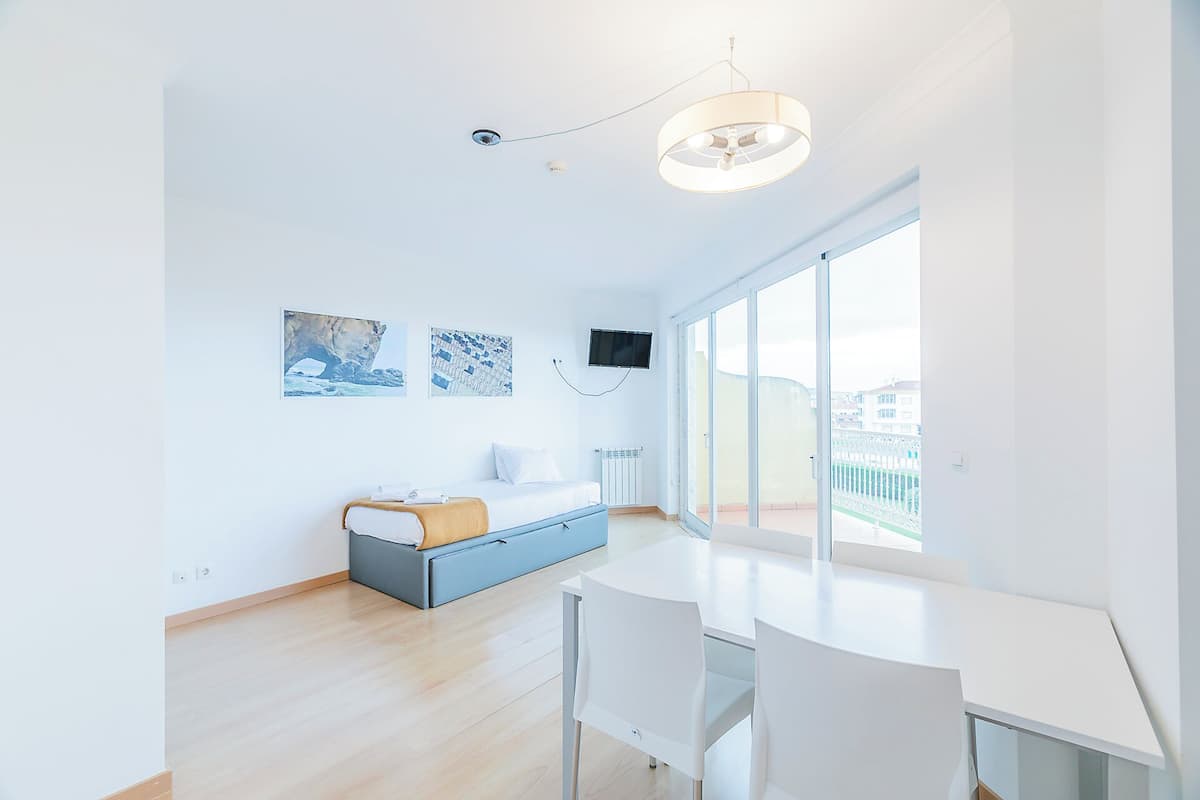 Una habitación de hotel moderna con cama, escritorio, silla, televisor y ventanas amplias.
