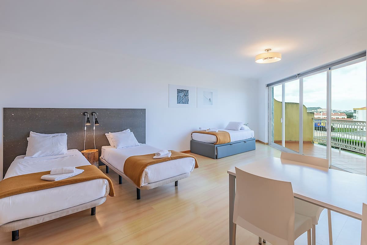 Una habitación de hotel moderna con dos camas, un escritorio y un balcón con vistas.