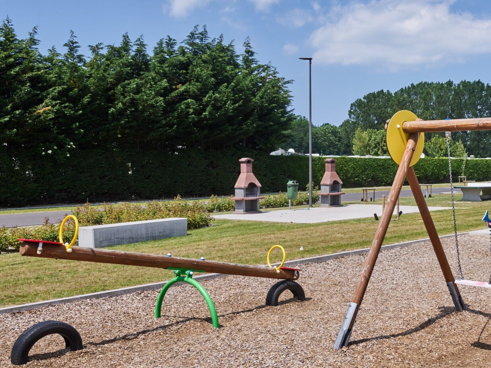 Un parque infantil con sube y bajas y columpios.