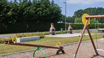 Un parque infantil con sube y bajas y columpios.