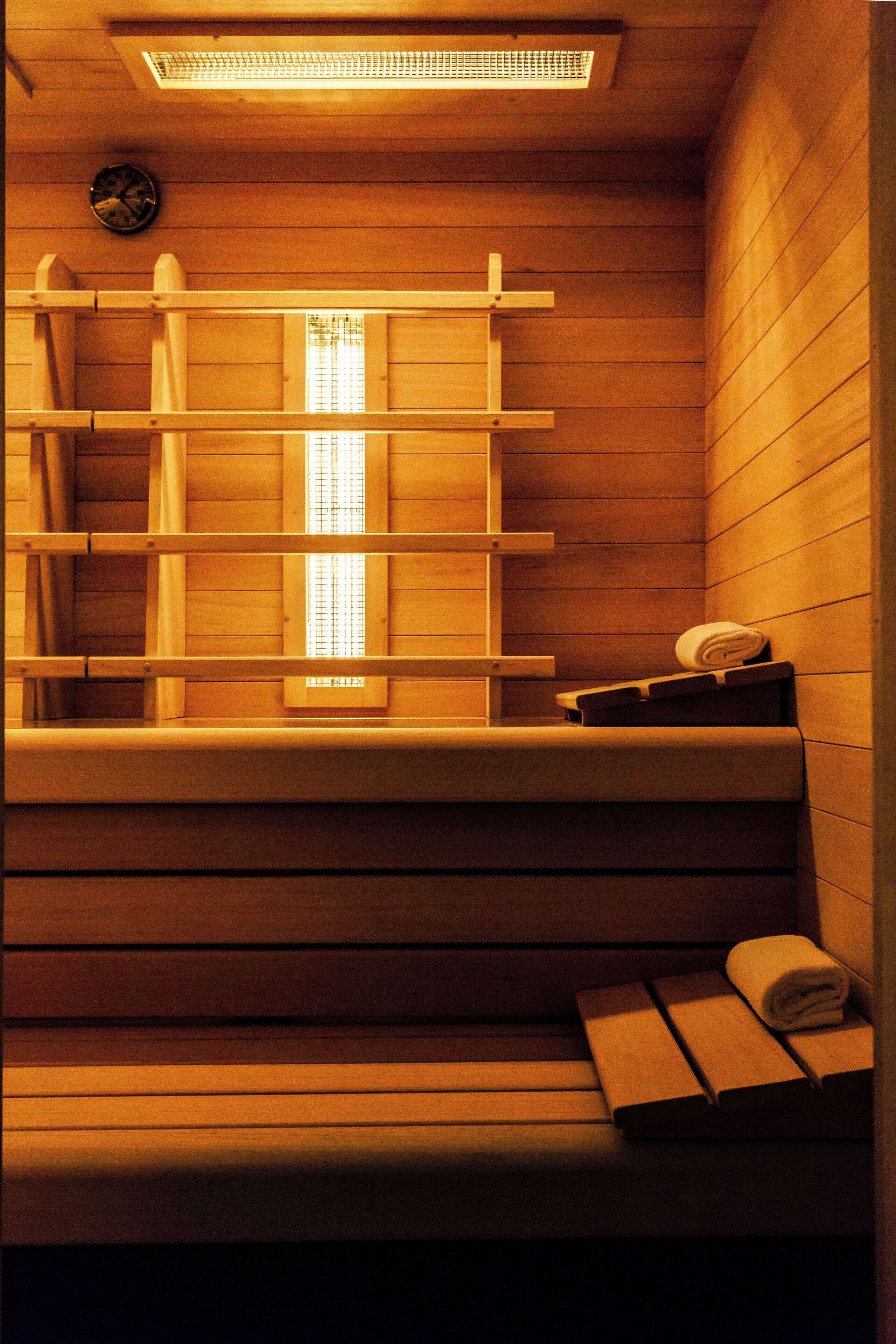 Un sauna avec des bancs en bois, un porte-serviettes et une horloge au mur.