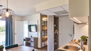 A modern kitchen with a built-in stove, a sink, and a dining area with a table and chairs. - Holiday Suites Nieuwpoort (Nieuwpoort)