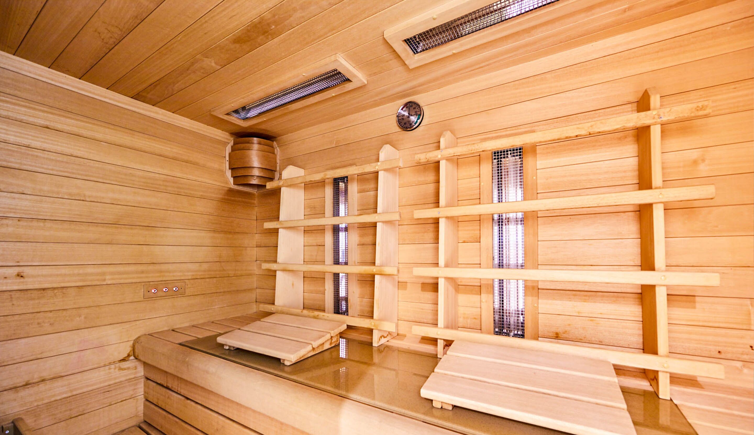 A wooden sauna with benches and a steam vent.