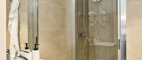 A modern bathroom with a glass-enclosed shower, a white sink, and a mirror above it.