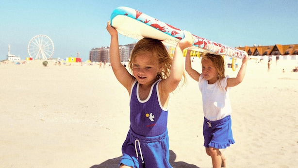 Two children on a sandy beach, one holding a surfboard. - Holiday Suites Nieuwpoort (Nieuwpoort)
