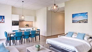 A modern hotel room with a bed, a dining area, and a kitchenette. - Holiday Suites Nieuwpoort (Nieuwpoort)