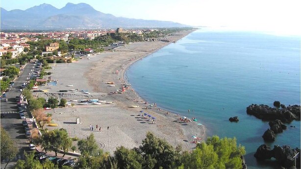 A coastal town with a beach, parked cars, and buildings in the background. - Villaggio Camping Orchidea (Grisolia)