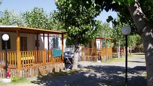 A row of wooden cabins with balconies, a gravel path, and a street lamp. - Villaggio Camping Orchidea (Grisolia)