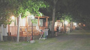 A row of wooden cabins with a deck, a clothesline, and a barbecue grill. - Villaggio Camping Orchidea (Grisolia)