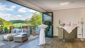 A modern room with a large sliding glass door leading to an outdoor patio. Inside, there is a seating area with a sofa and a table with a candle holder. - Romantik Hotel Ahrenberg (Bad Sooden-Allendorf)
