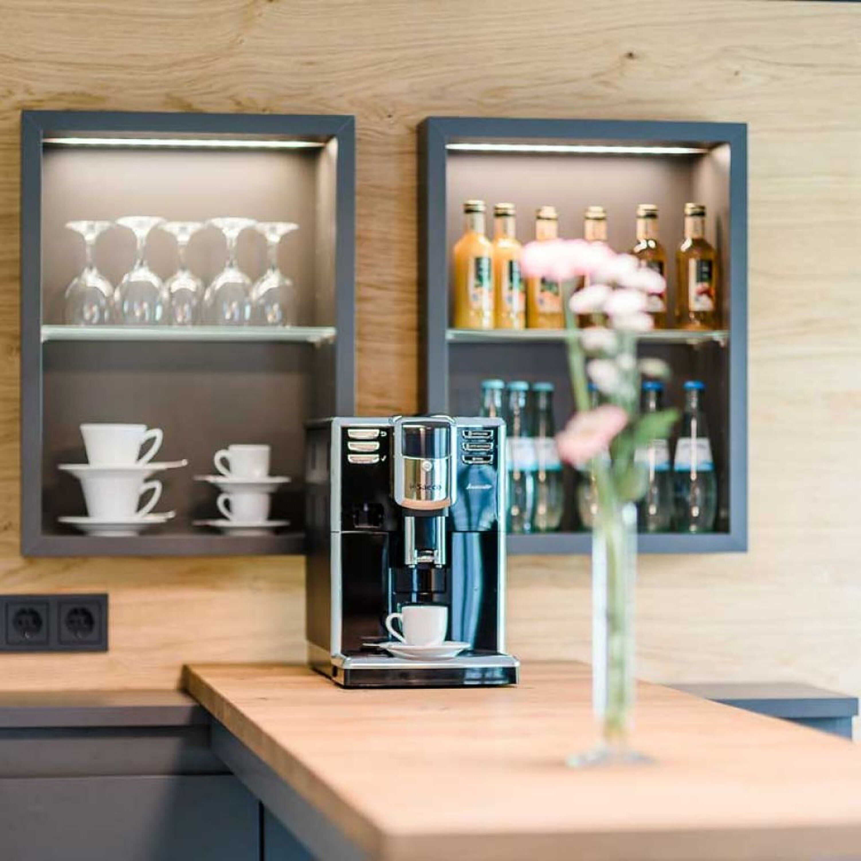 Une machine à café est pos ée sur un comptoir, et au-dessus, un cadre présente une collection de tasses et de verres.