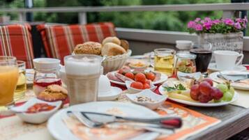 A breakfast table with various food items, drinks, and utensils.
