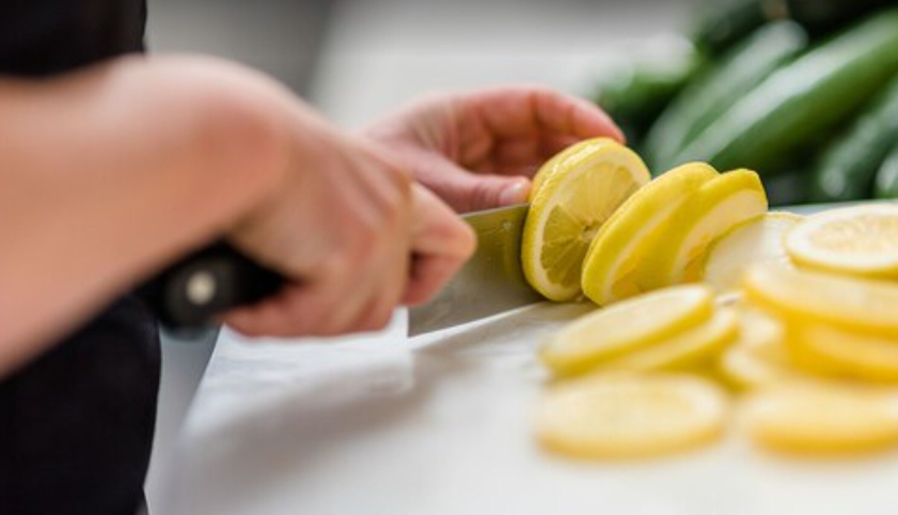 Une personne est en train de couper des citrons sur une planche à découper blanche.
