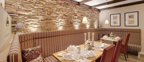 Un restaurante con pared de piedra, asientos a rayas y una mesa de madera dispuesta para comer.