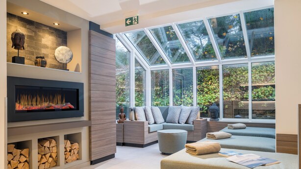 A modern spa area with a fireplace, seating, and a glass ceiling. - Romantik Hotel Ahrenberg (Bad Sooden-Allendorf)