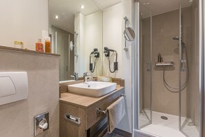 A modern bathroom with a glass-enclosed shower, a sink with a vanity, and a mirror. - Romantik Hotel Ahrenberg (Bad Sooden-Allendorf)