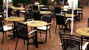 An outdoor cafe area with tables and chairs, a brick building with a sign reading "Konoba Restaurant Bistro", and umbrellas. - Hotel Konoba Restaurant - Bistro (Meckenheim)