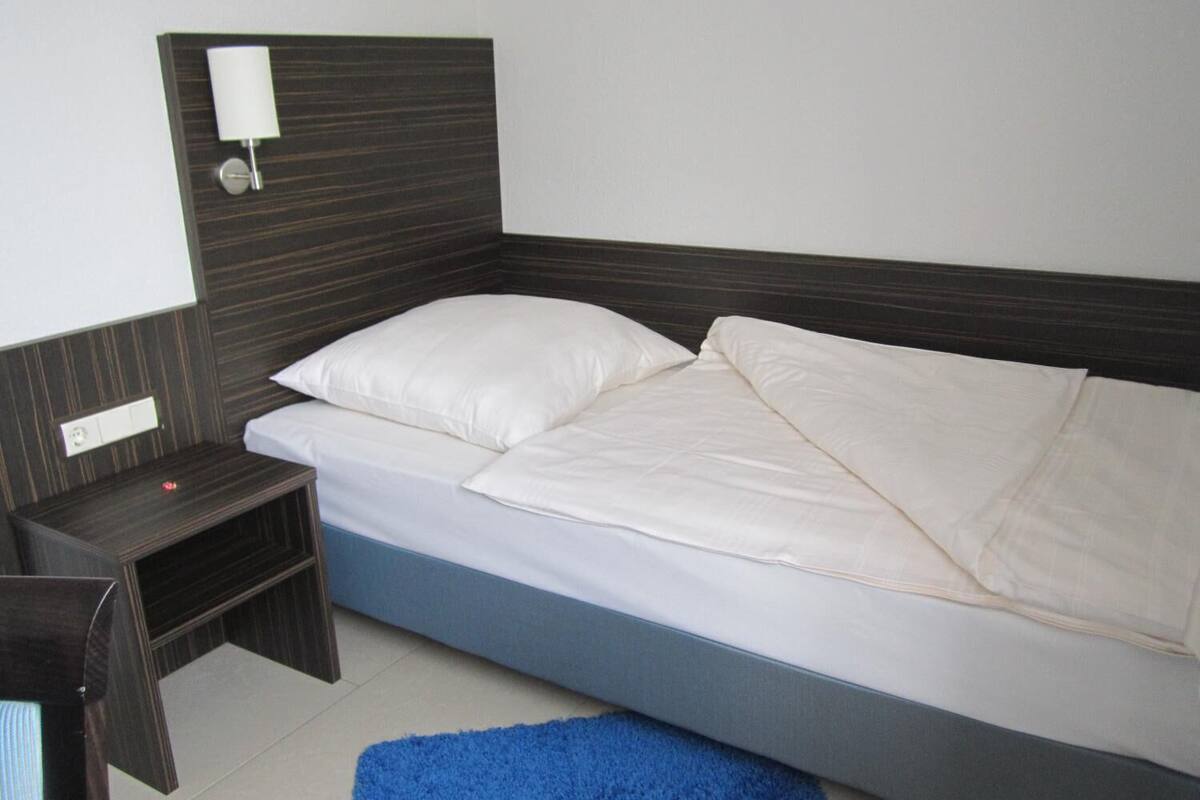Une chambre à coucher avec un lit, une table de chevet, une lampe et un tapis bleu.