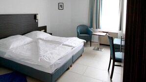 A hotel room with a bed, a desk, a chair, and a window with curtains. - Hotel Konoba Restaurant - Bistro (Meckenheim)