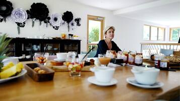 A dining area with a wooden table set for breakfast, including various dishes and condiments.