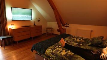 Une chambre à coucher comprenant un lit, une commode, un bureau, une chaise, un téléviseur et un radiateur.