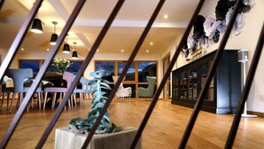 A modern interior with a dining area, wooden flooring, and a view through a window. - Maison d'hôtes & Spa La Scierie (Salins-les-Bains)