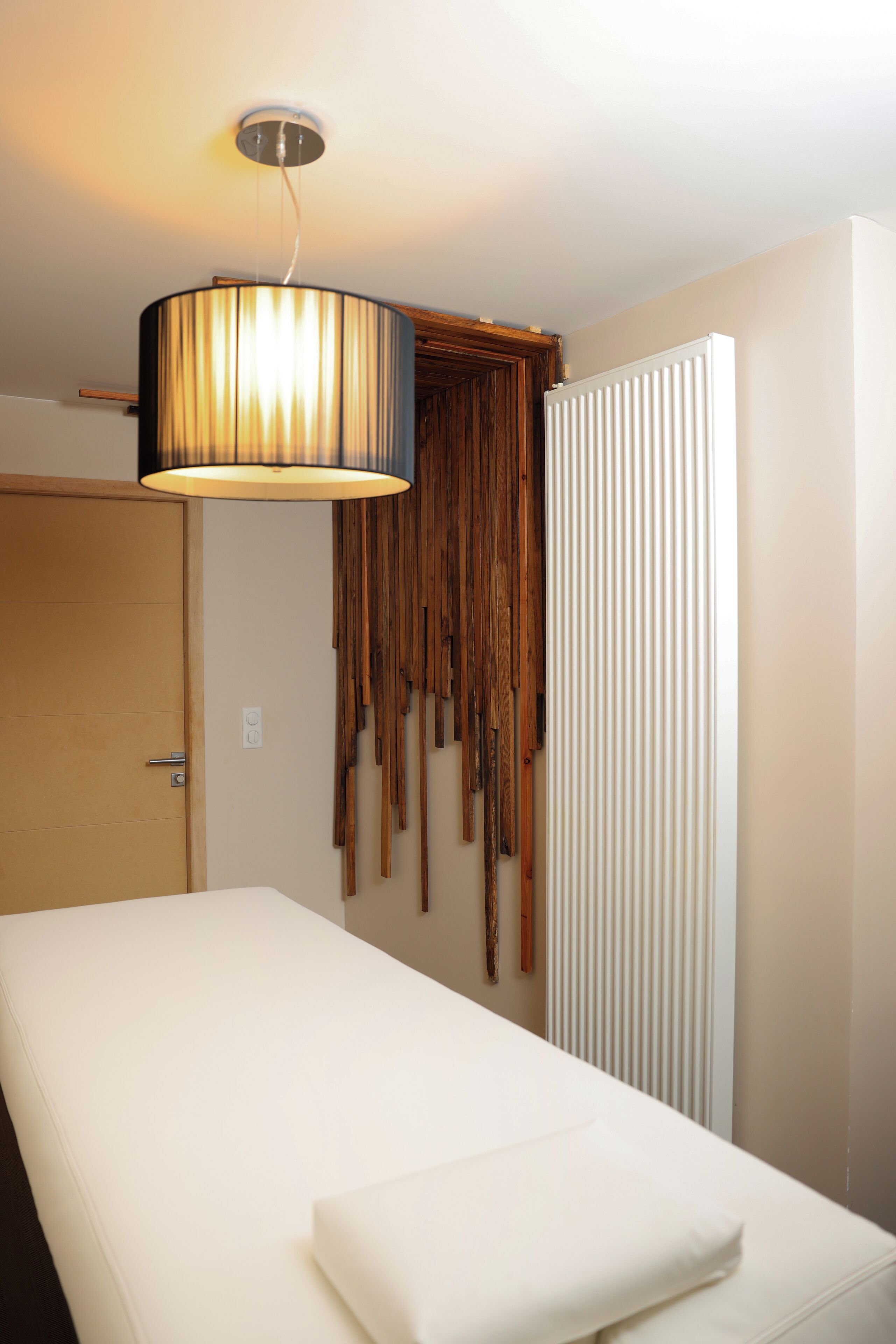 A hotel room with a bed, a hanging wooden decor, and a ceiling light fixture.
