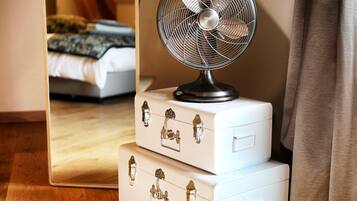 Een kamer met een bed, een ventilator en een spiegel die een deel van de kamer weerspiegelt.