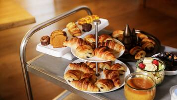 Un plateau contenant un assortiment de viennoiseries et de desserts, notamment des croissants et des muffins, présenté sur un présentoir en métal.