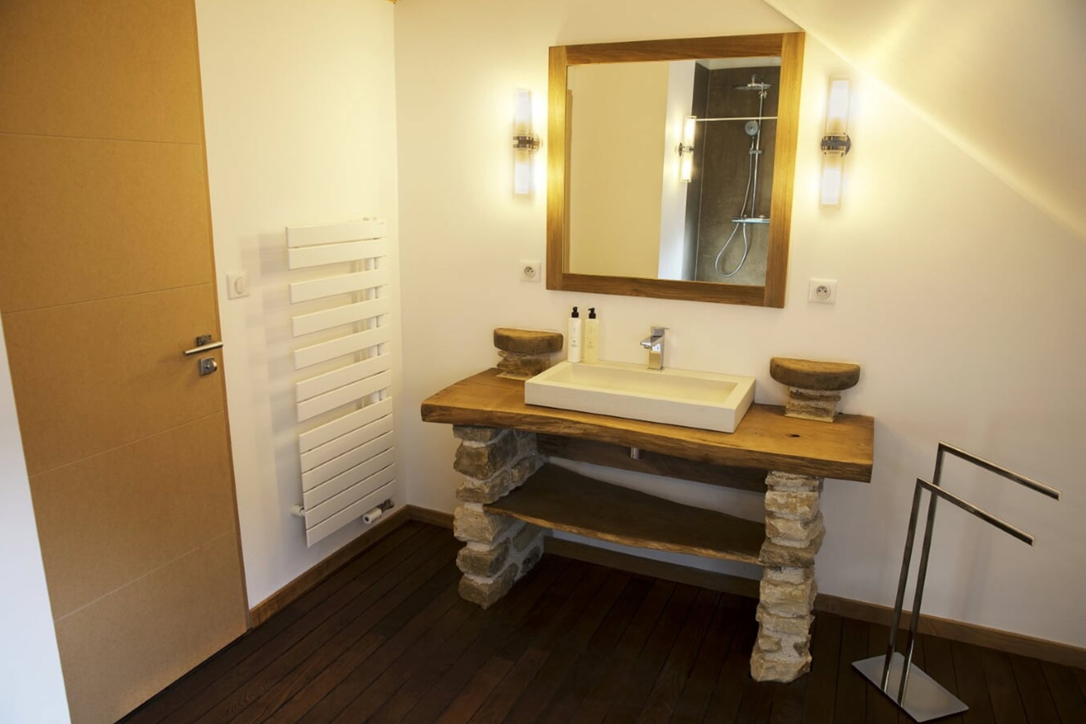 A bathroom with a stone sink, wooden countertop, and a mirror with lights.