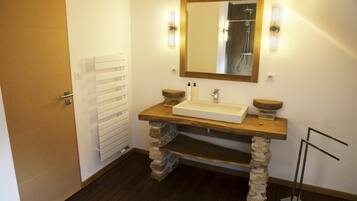 A bathroom with a stone sink, wooden countertop, and a mirror with lights.