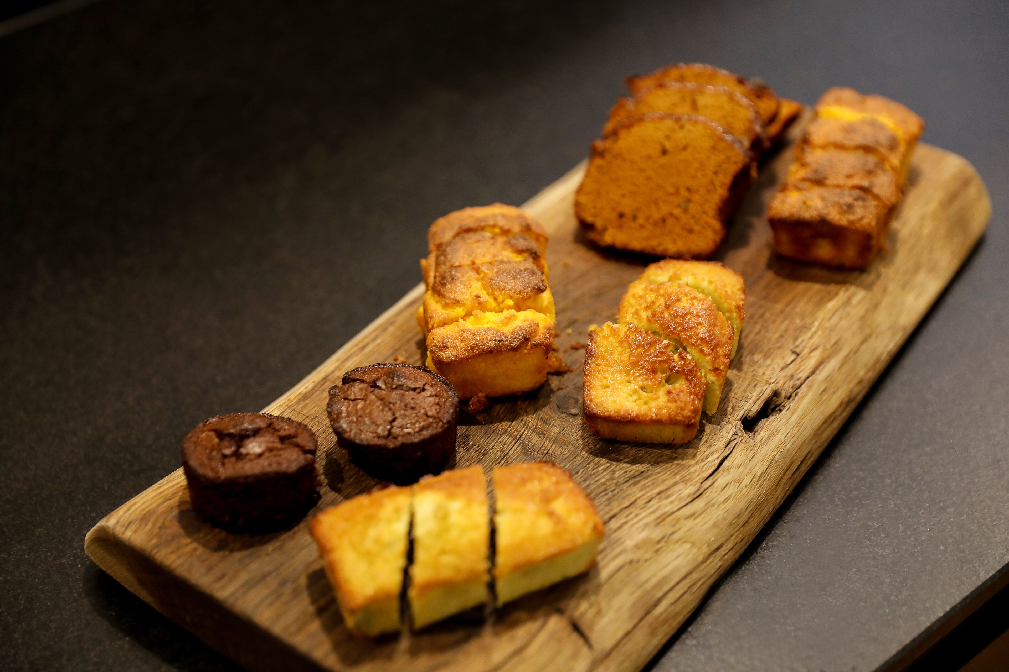 Ein Holzboden mit verschiedenen Backwaren, darunter Muffins und einem Brot.