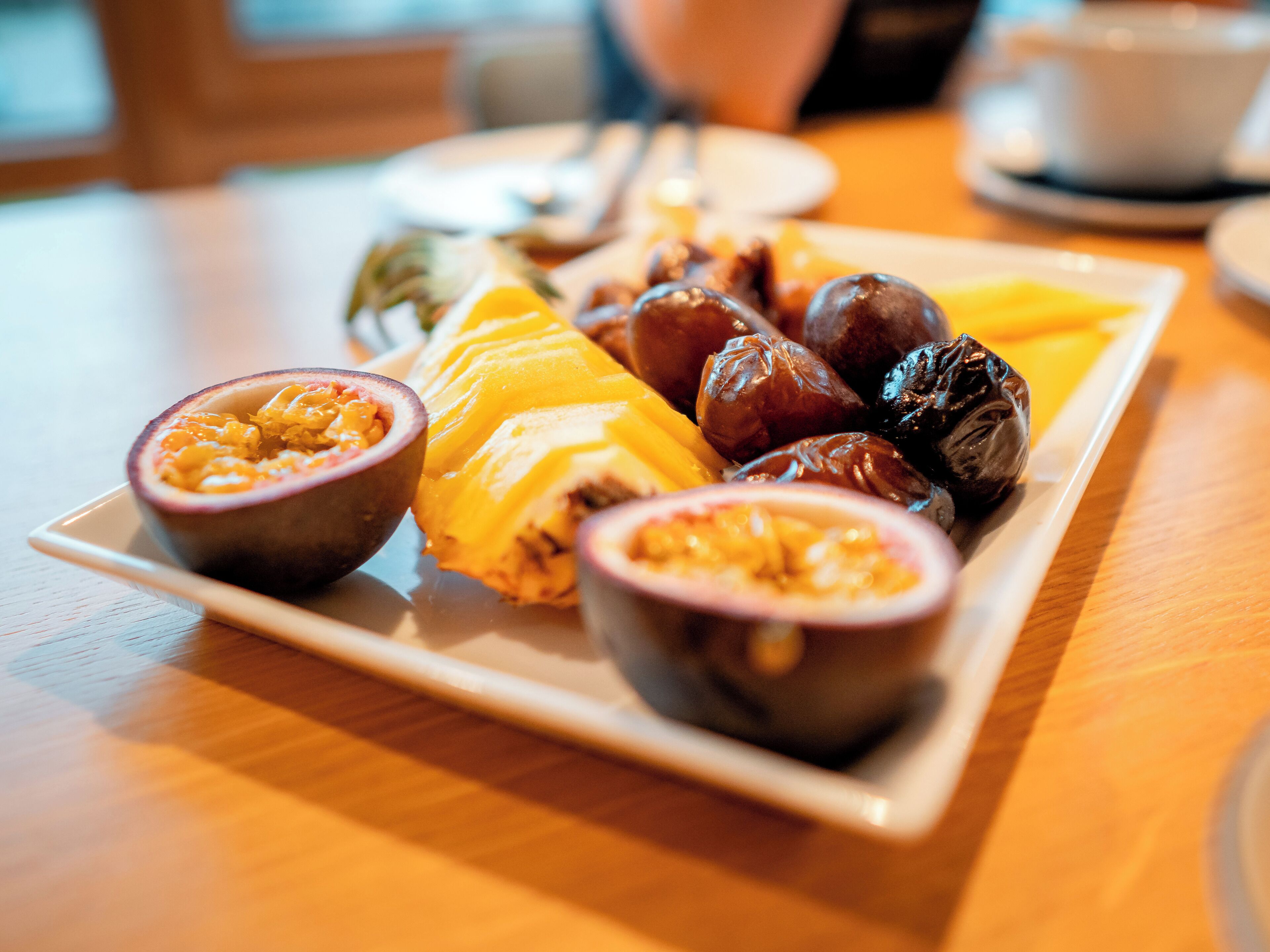 A plate of assorted fruits and nuts on a wooden table.