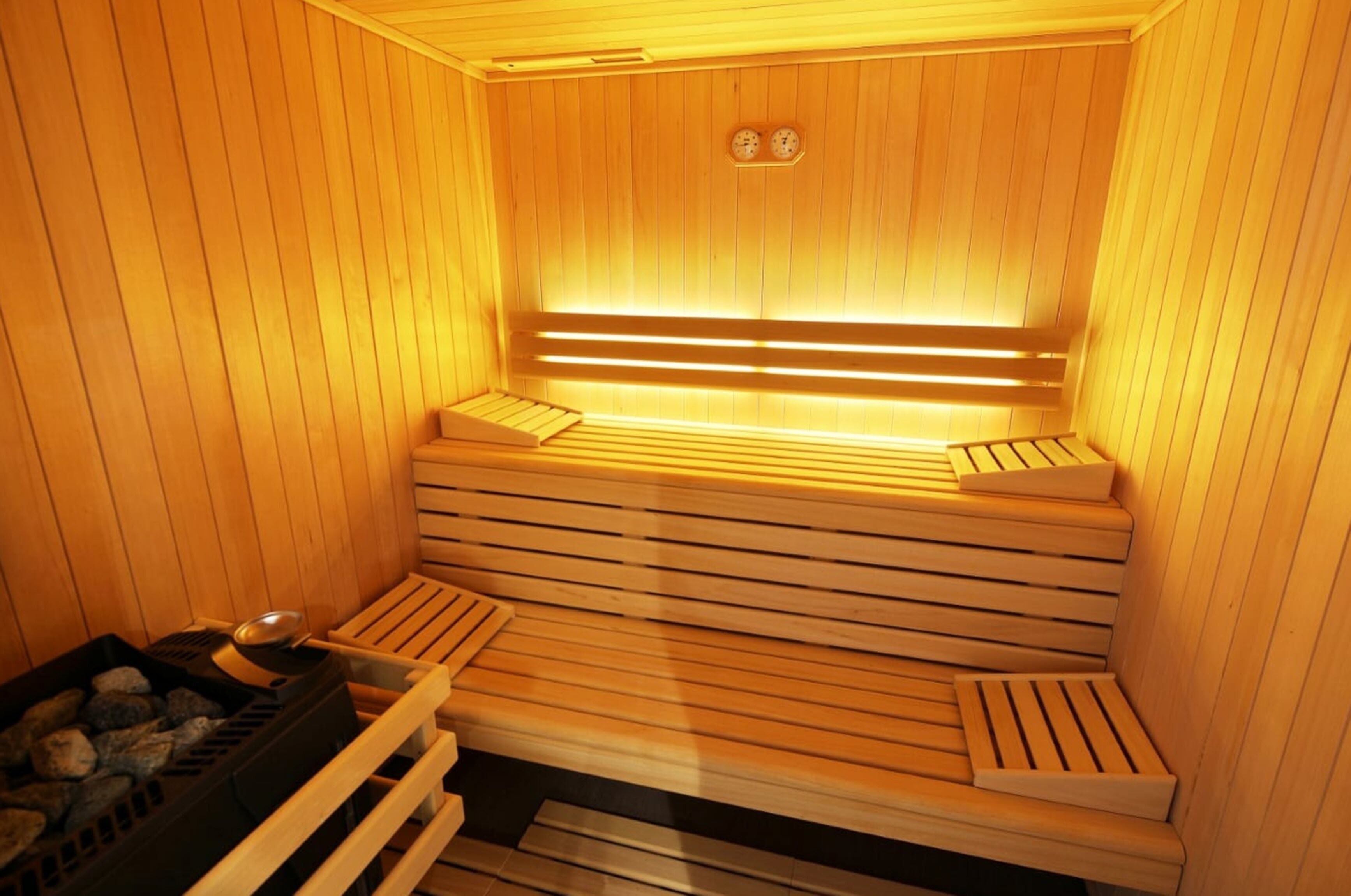 A wooden sauna with benches and a heating element.