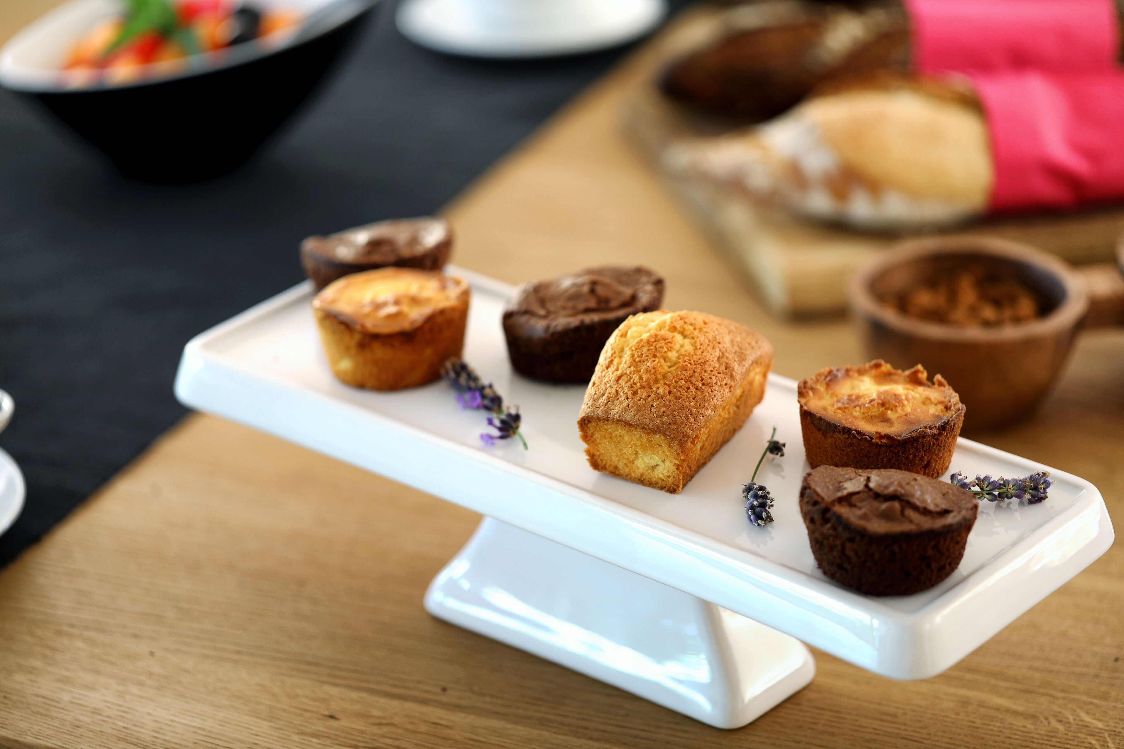Een wit dienblad met diverse gebakjes op een houten tafel.