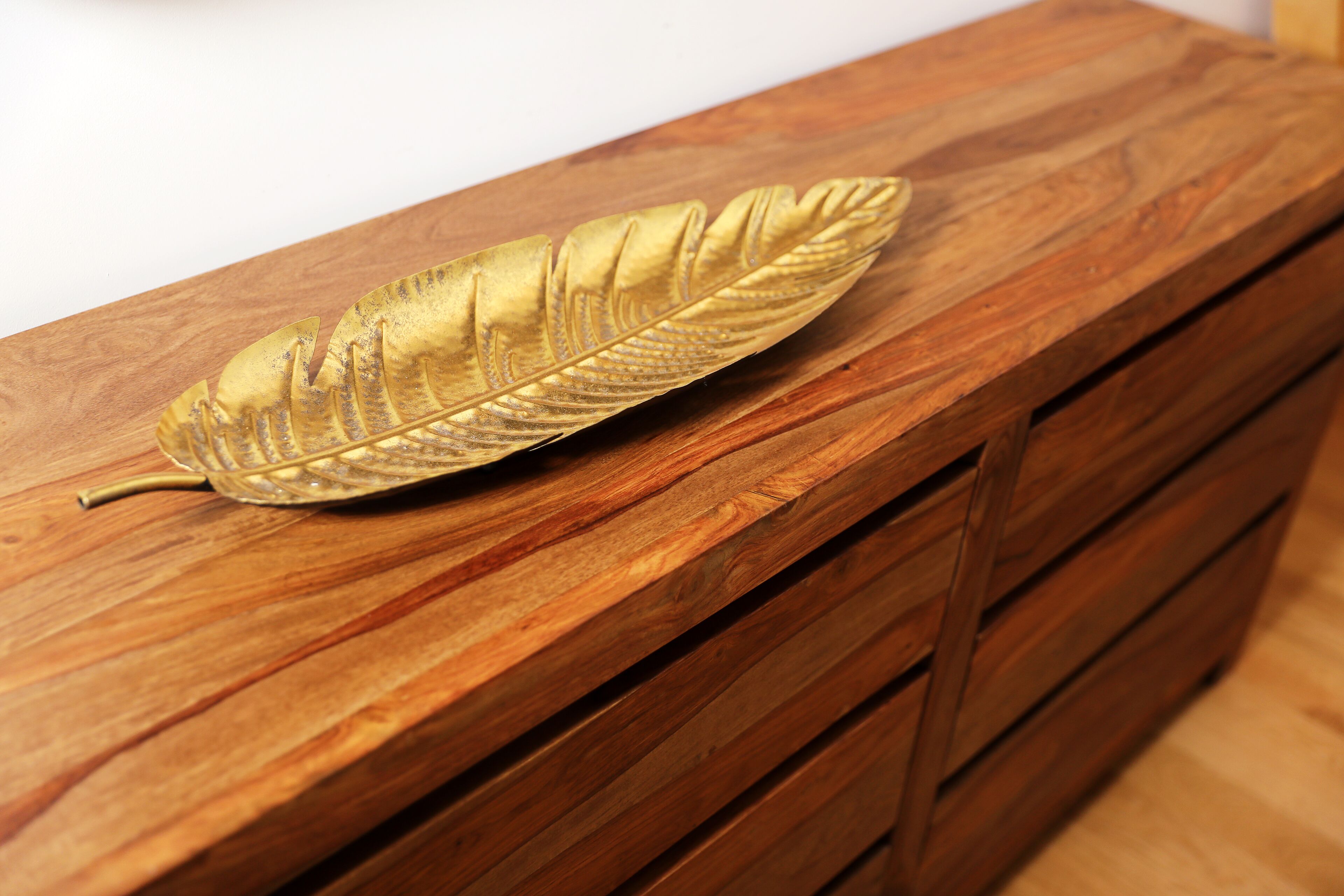 Een houten dressoir met lades en bladgoud decoratie.