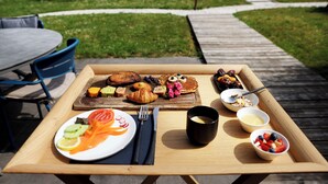 A breakfast tray with croissants, muffins, pancakes, and fresh fruit on a wooden table outdoors. - Maison d'hôtes & Spa La Scierie (Salins-les-Bains)