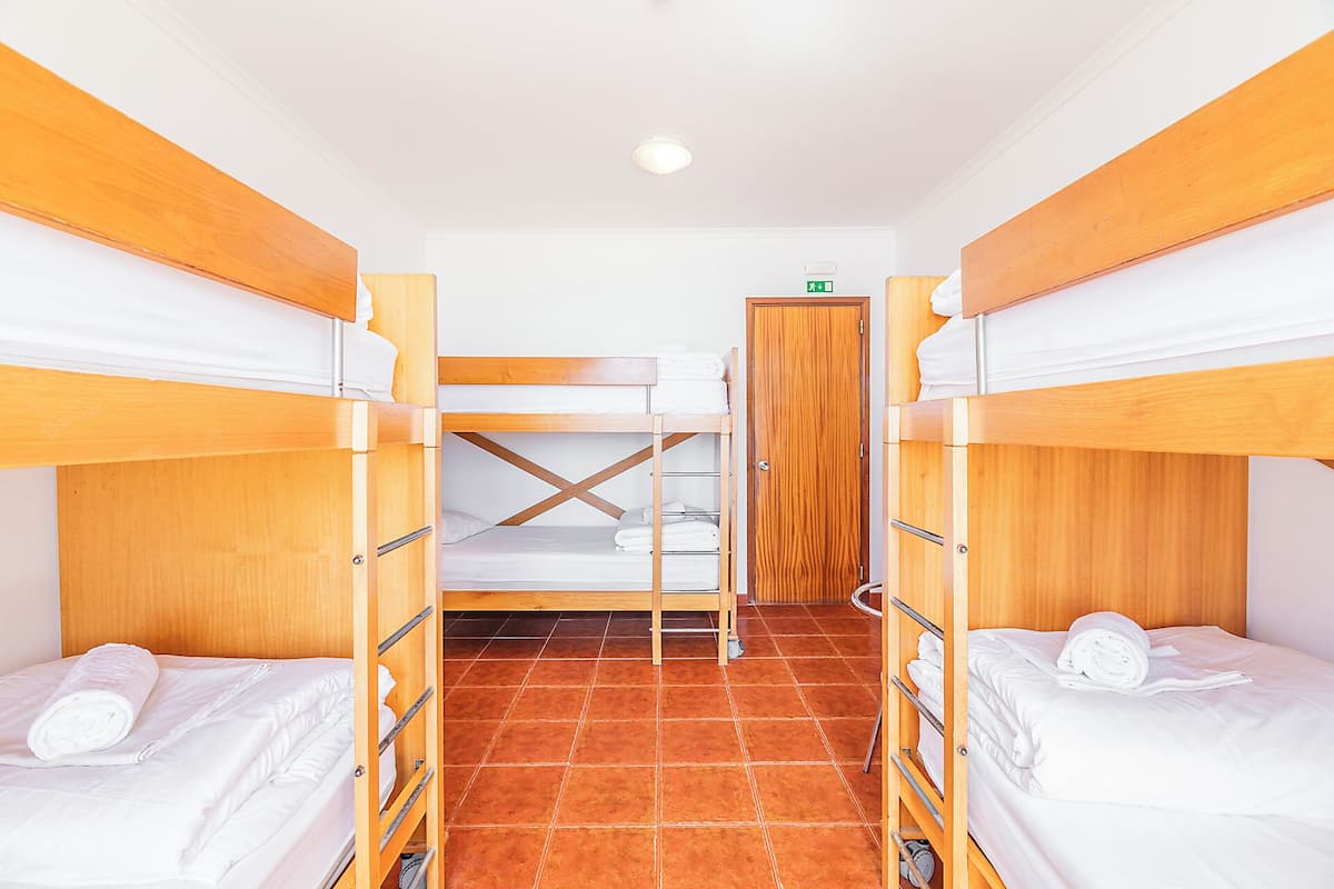 A room with bunk beds, a wooden door, and a tiled floor.