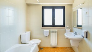 A small, clean bathroom with a toilet, sink, and bathtub. - HI Areia Branca – Pousada de Juventude - Hostel (Lourinha)
