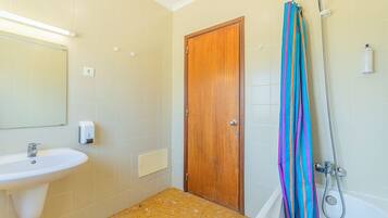 Un baño con lavamanos, puerta de madera, ducha y cortina de ducha a rayas.
