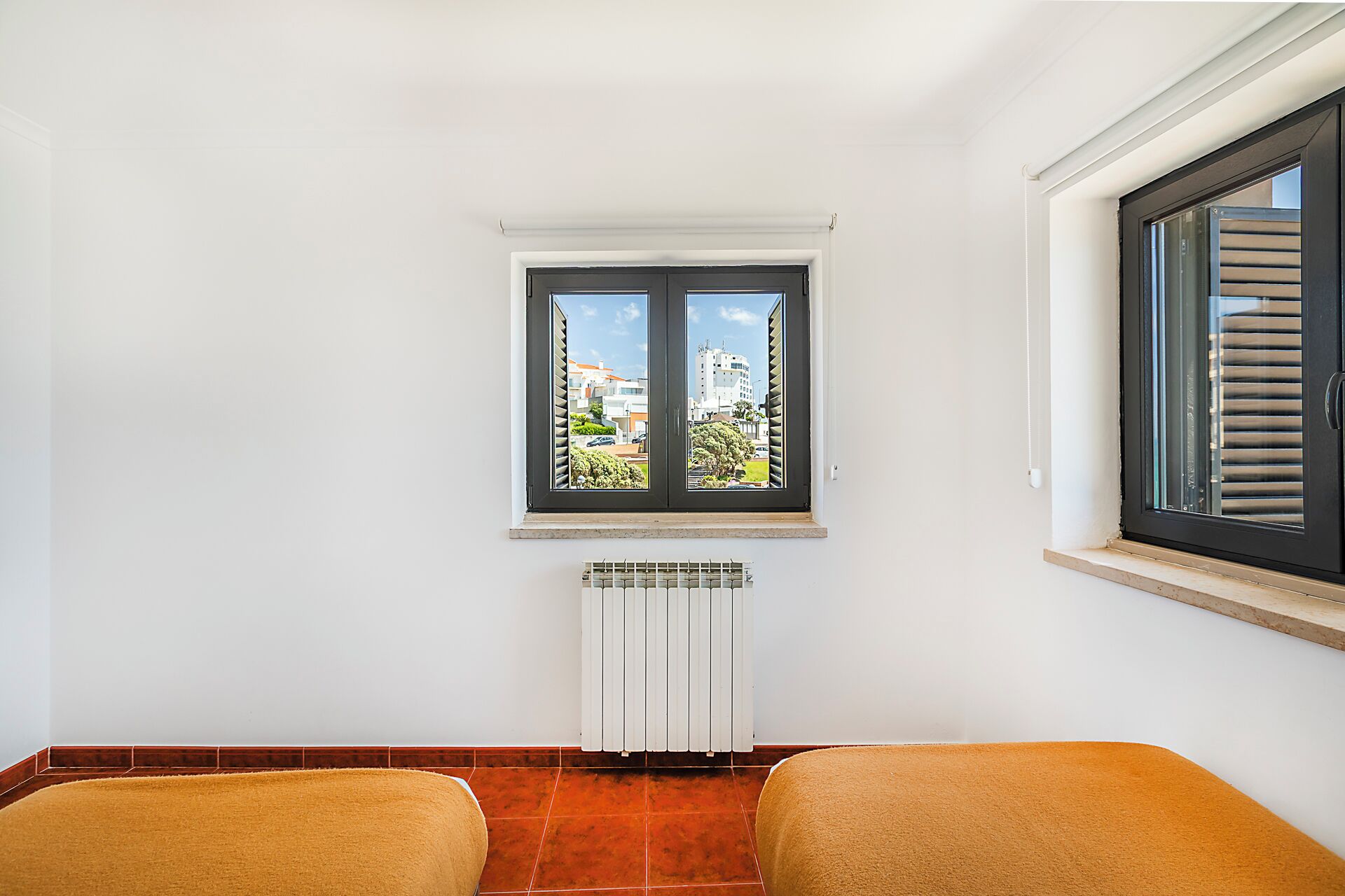 A room with a window, radiator, and two chairs.