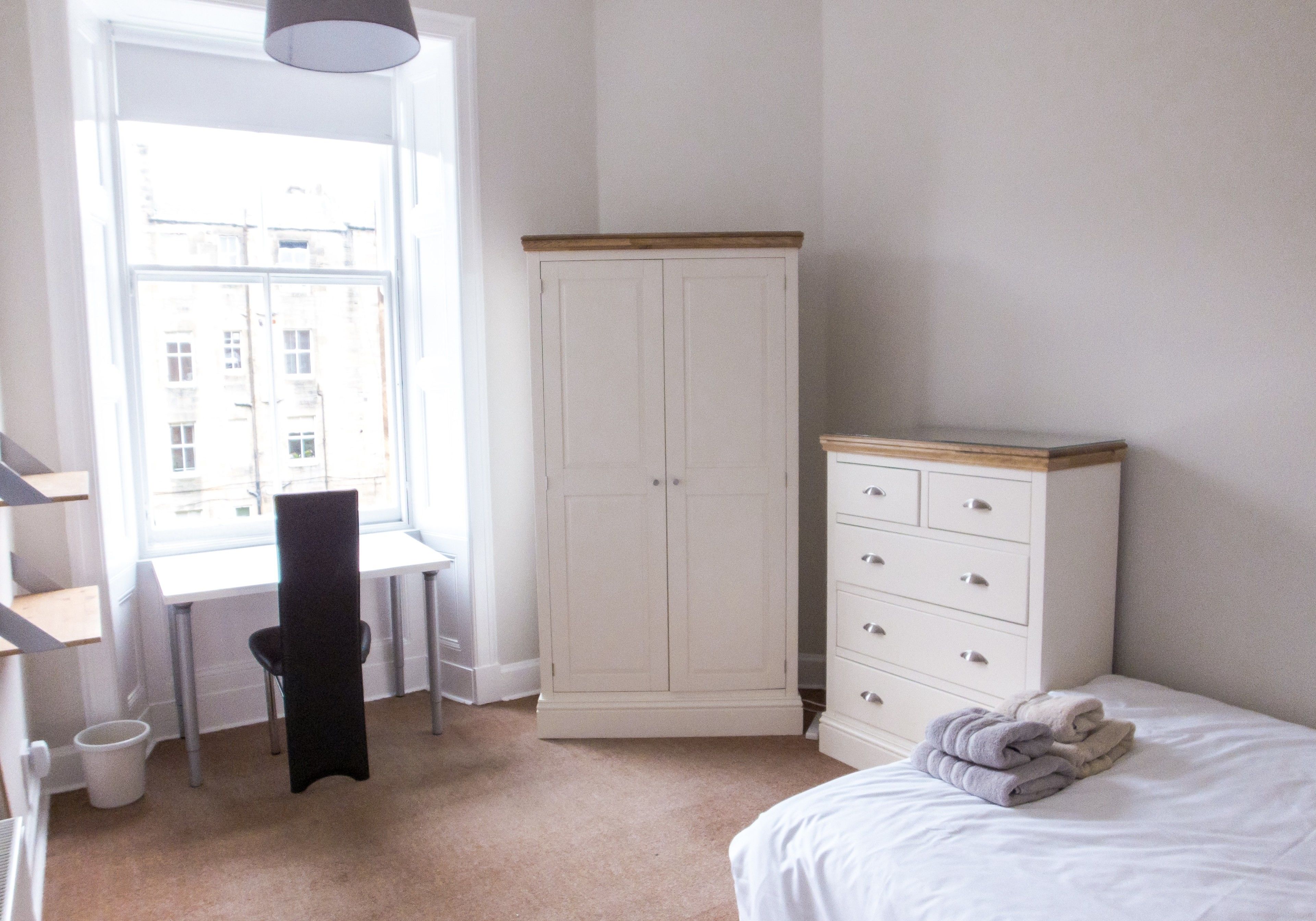 Ein Schlafzimmer mit Bett, Kleiderschrank, Schreibtisch und Stuhl.
