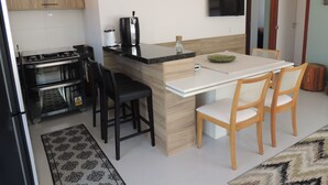 Eine moderne Küche mit Herd, Spüle und Essbereich mit Stühlen und Tisch.