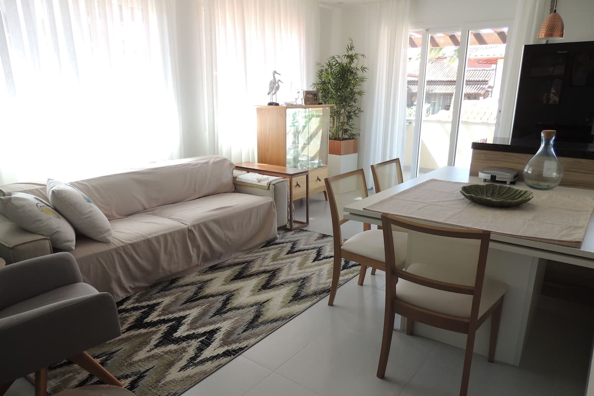 A living room with a sofa, chairs, a dining table, and a potted plant.
