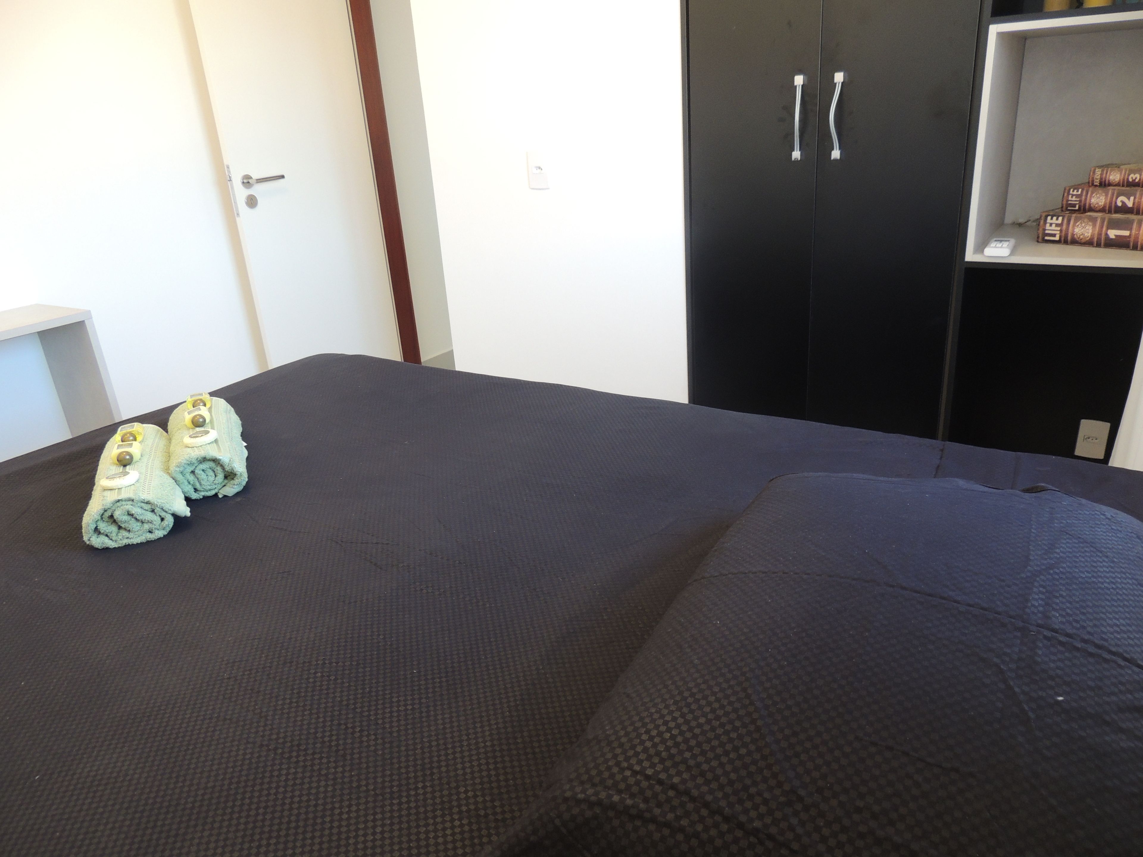 A room with a bed, a wardrobe, and a shelf with books.