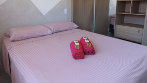 Ein ordentlich bezogenes Bett mit rosa Bettwäsche und zwei zusammengerollten Handtüchern mit goldenen Akzenten.