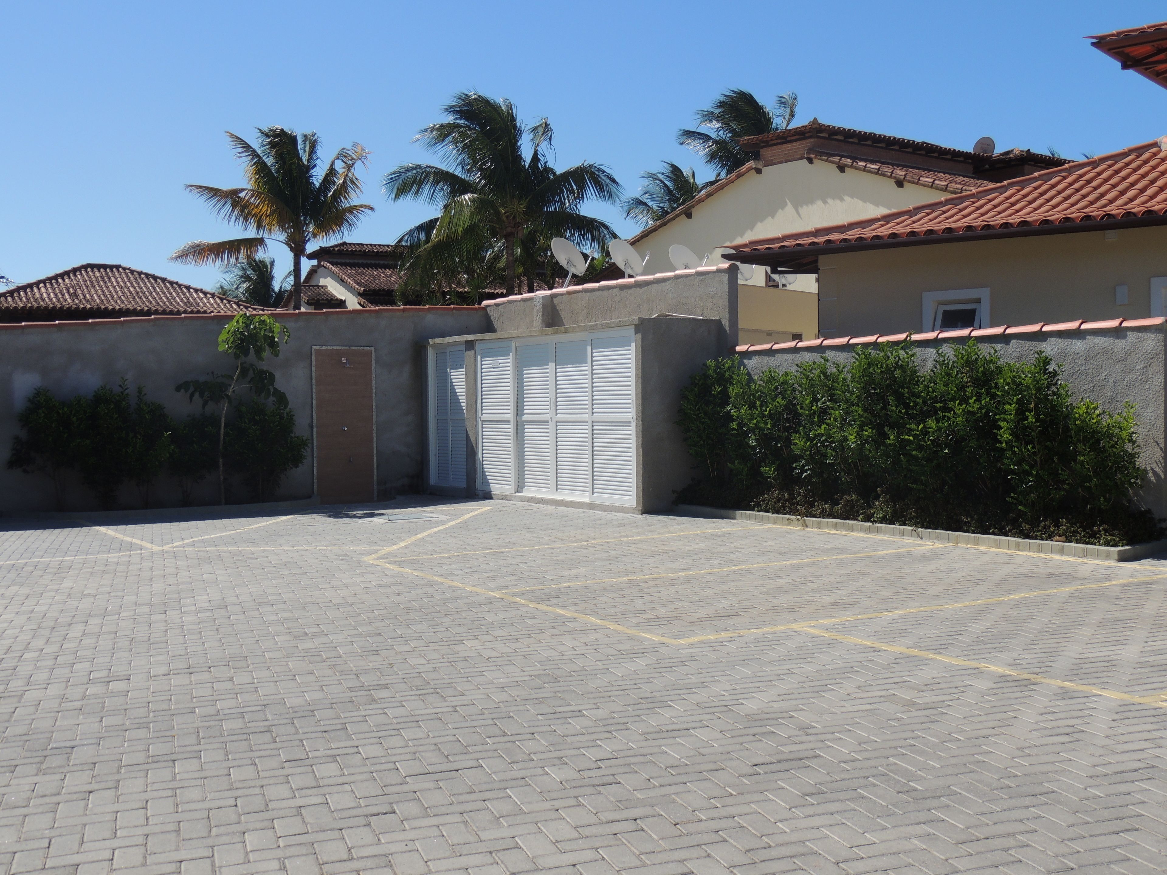 A parking area with a paved surface, a gated entrance, and a building with a tiled roof and satellite dishes.