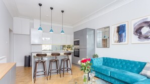 Una cocina moderna con taburetes de bar, un sofá azul y una mesa de centro con un jarrón de flores.