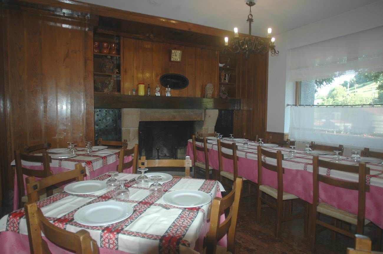 Ein Essbereich mit Holzvertäfelung, einem Kamin und gedeckten Tischen.