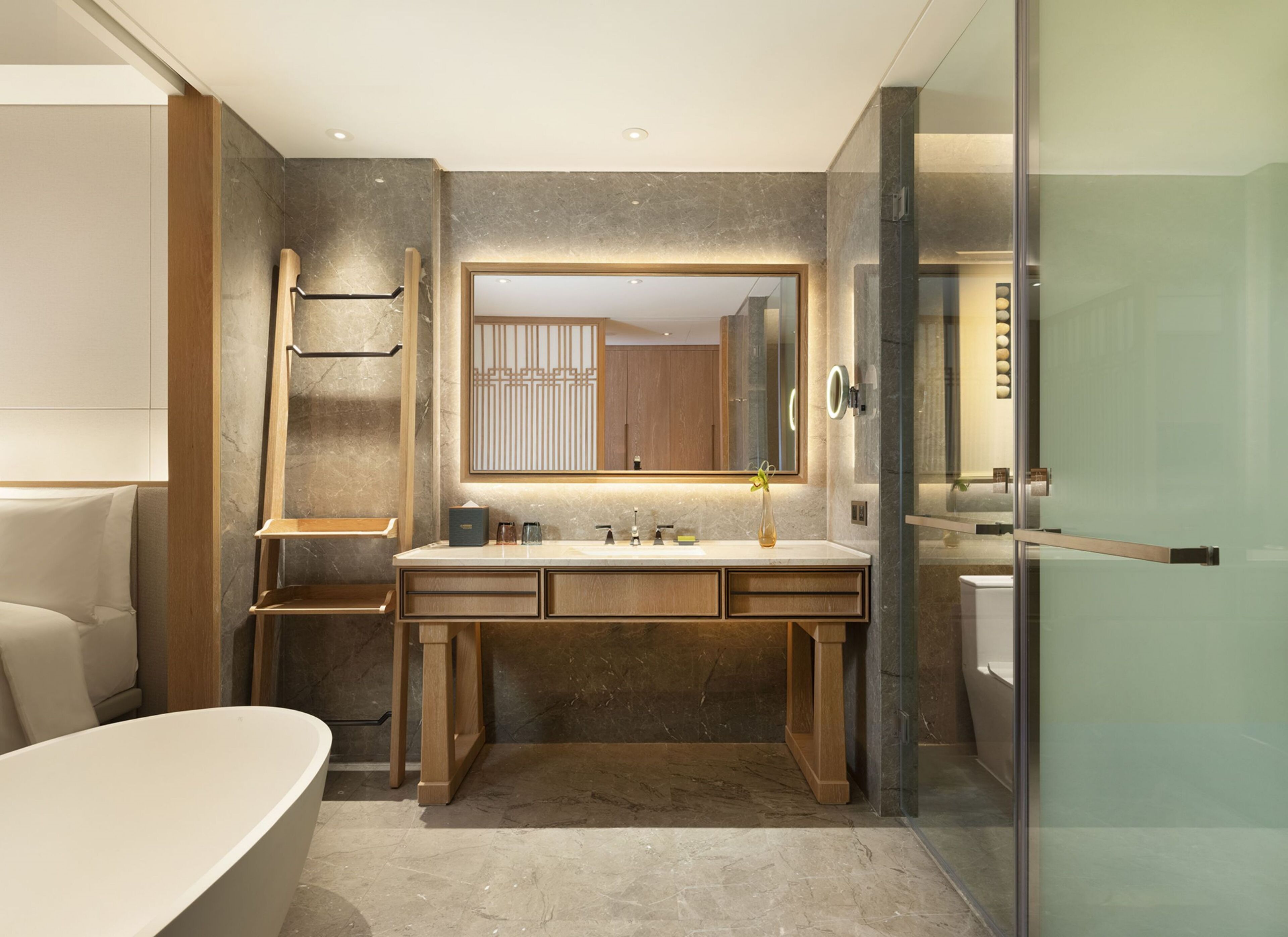 A modern bathroom with a freestanding bathtub, a large mirror, and a vanity with a marble countertop.